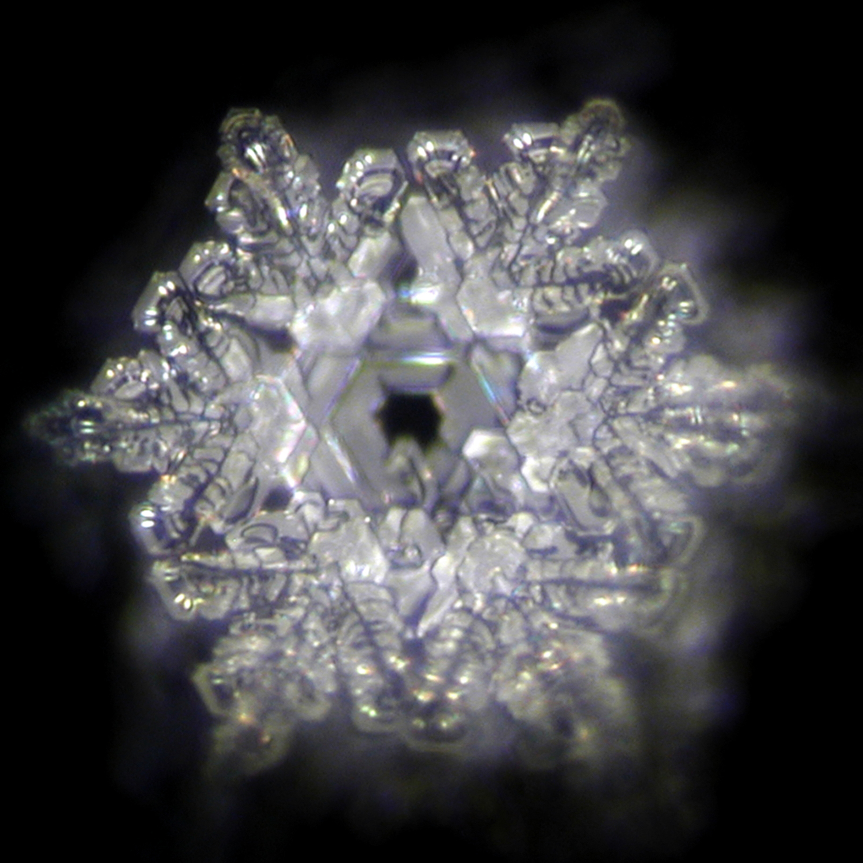 Foto eines Eiskristalls nach dem Emoto-Verfahren von aqua blue behandeltem Wasser. Es zeigt hohe Ordnung um eine hexagonale Basis.